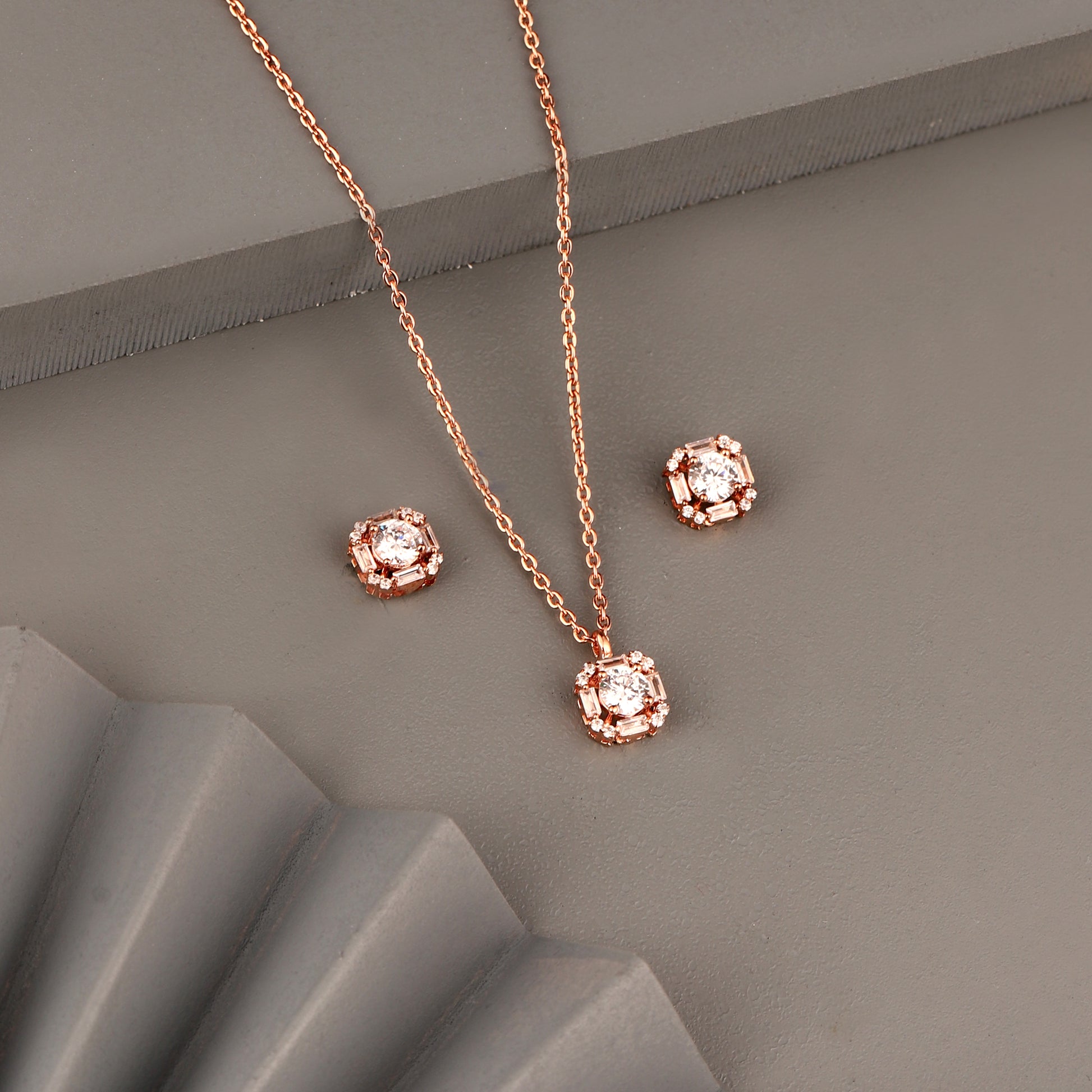 Rose gold pendant set in 925 silver with round center stone and geometric halo design including matching stud earrings