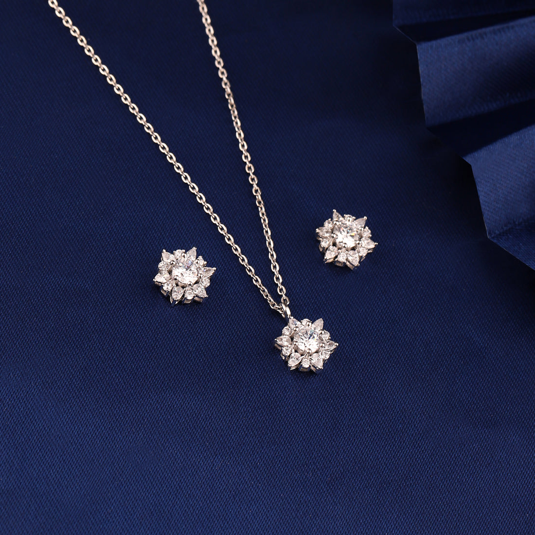 925 silver snowflake cluster pendant set displayed on blue fabric background