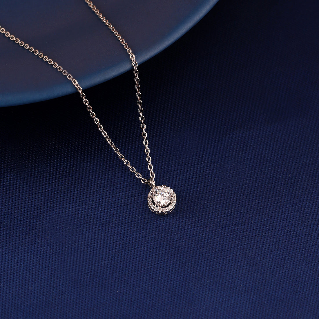 Round halo pendant necklace in 925 silver displayed on blue fabric background