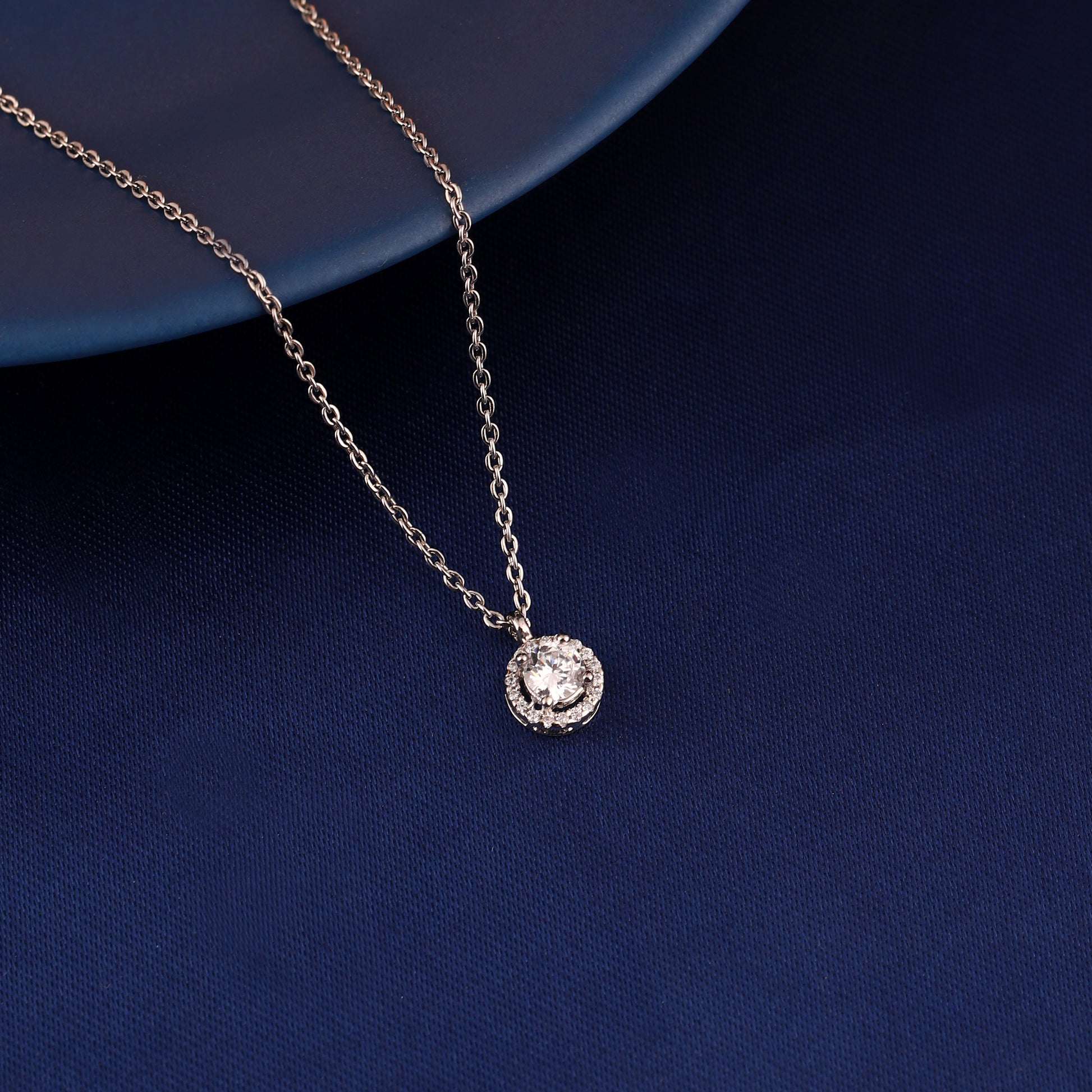 Round halo pendant necklace in 925 silver displayed on blue fabric background