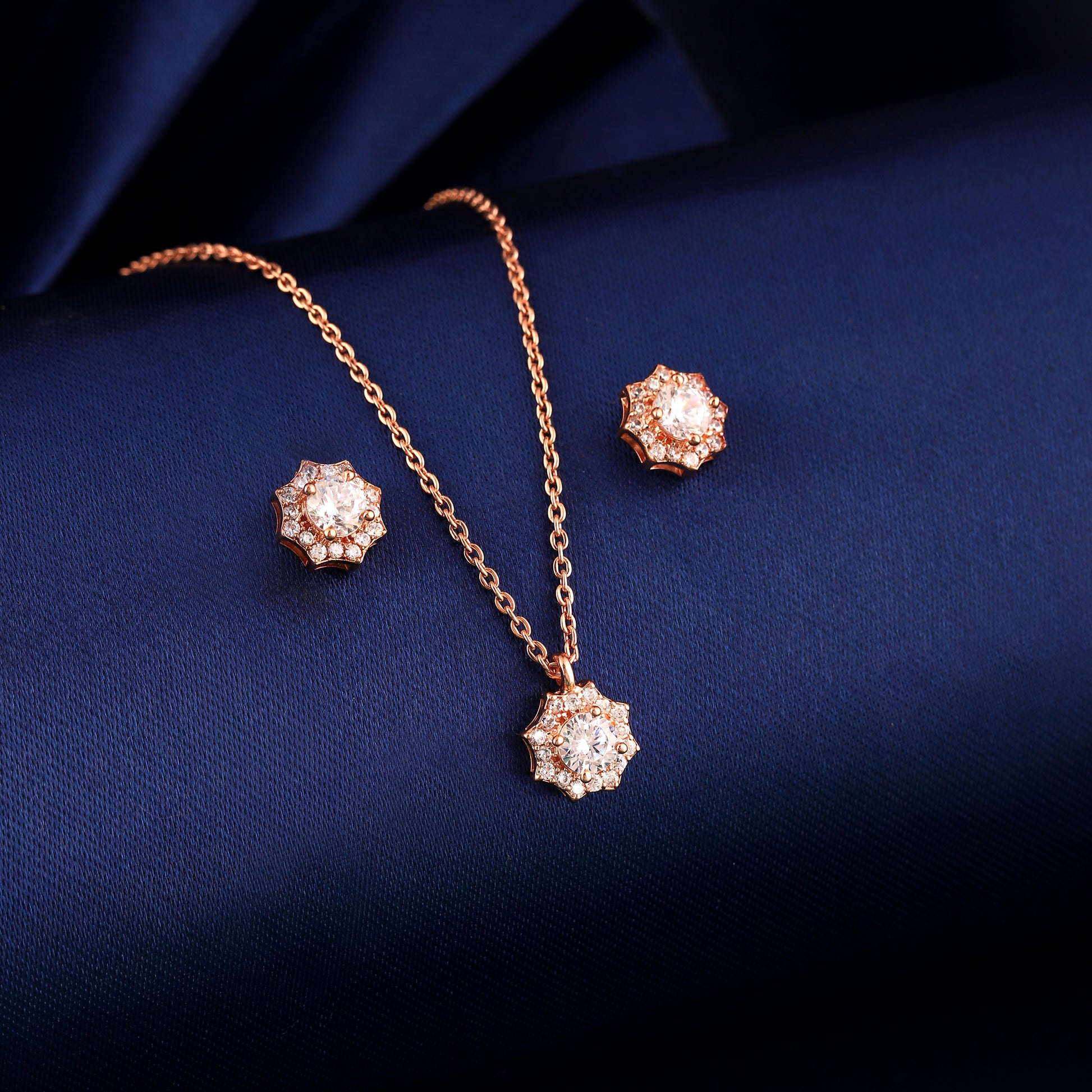 Rose gold 925 silver floral pendant set displayed on blue fabric background