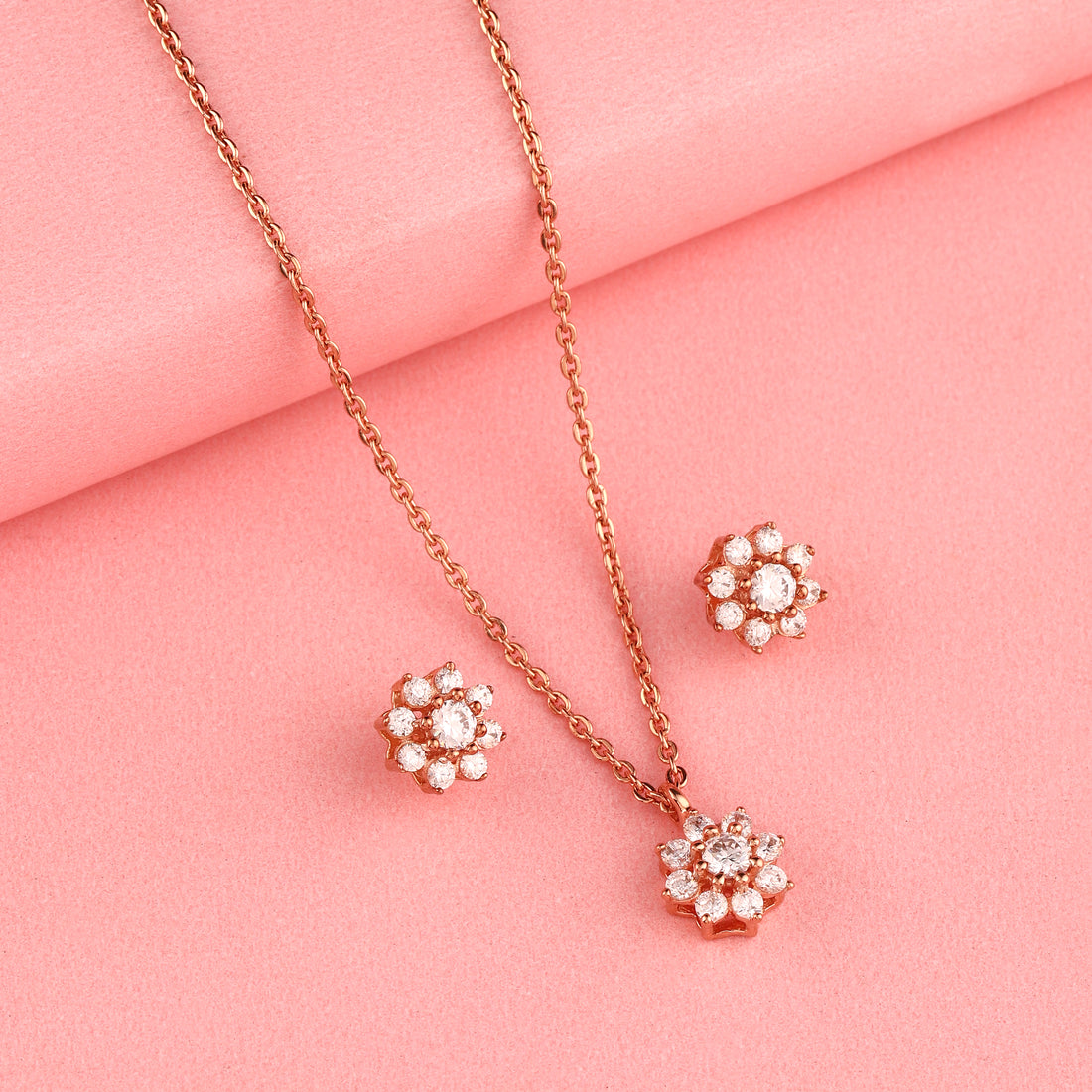 Rose gold floral 925 silver pendant and earrings set styled on pink background