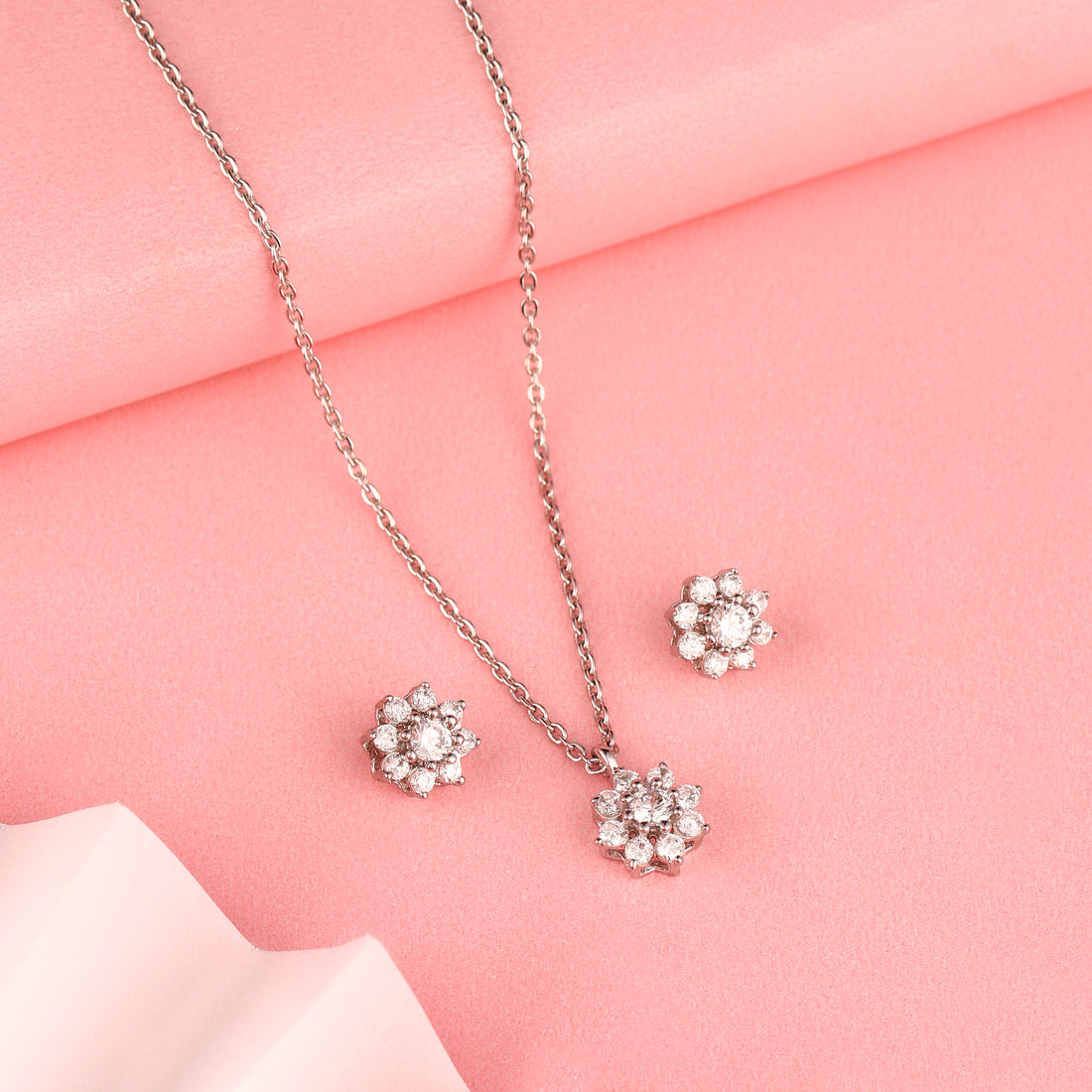 Floral 925 silver pendant and earrings styled on soft pink background