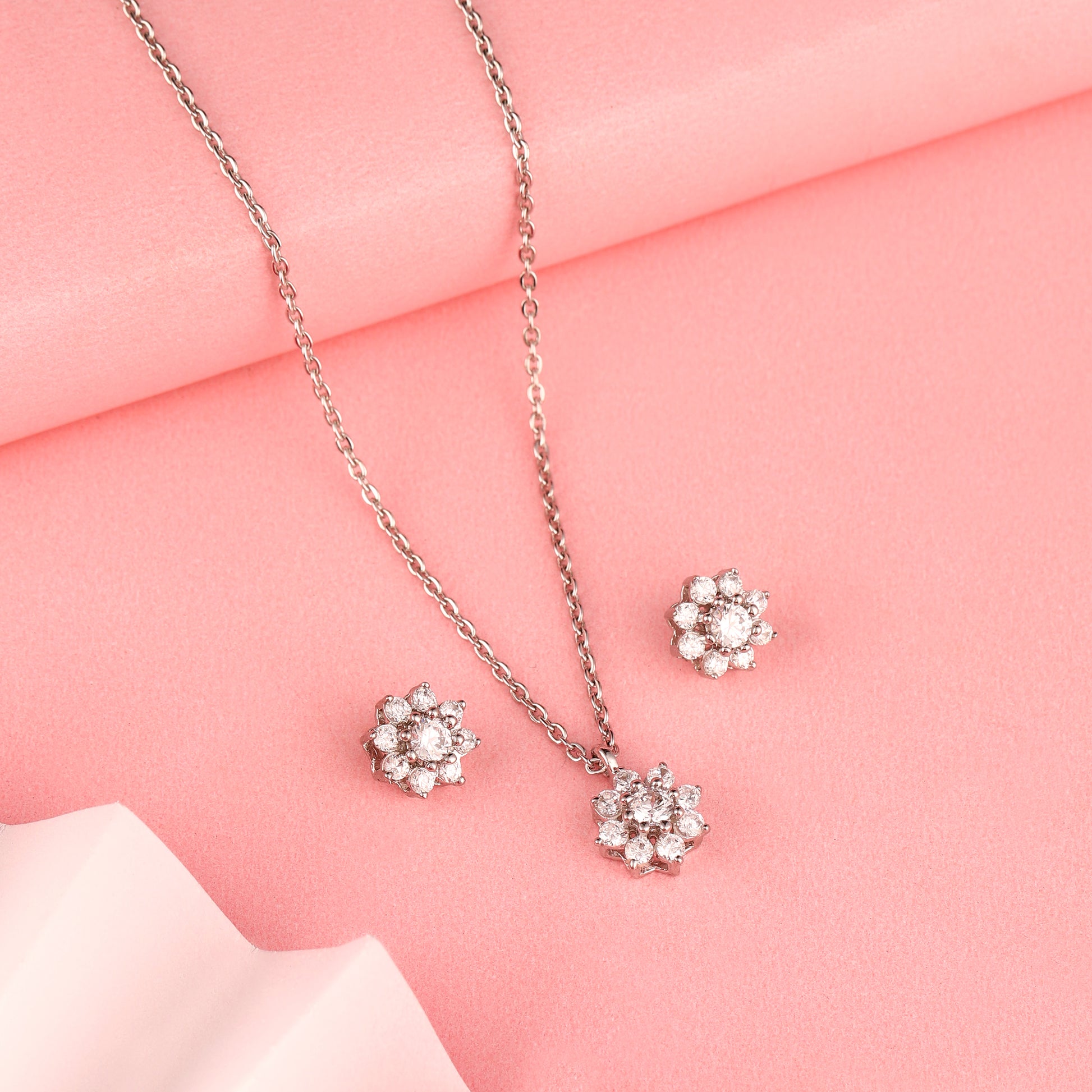 Floral 925 silver pendant and earrings styled on soft pink background