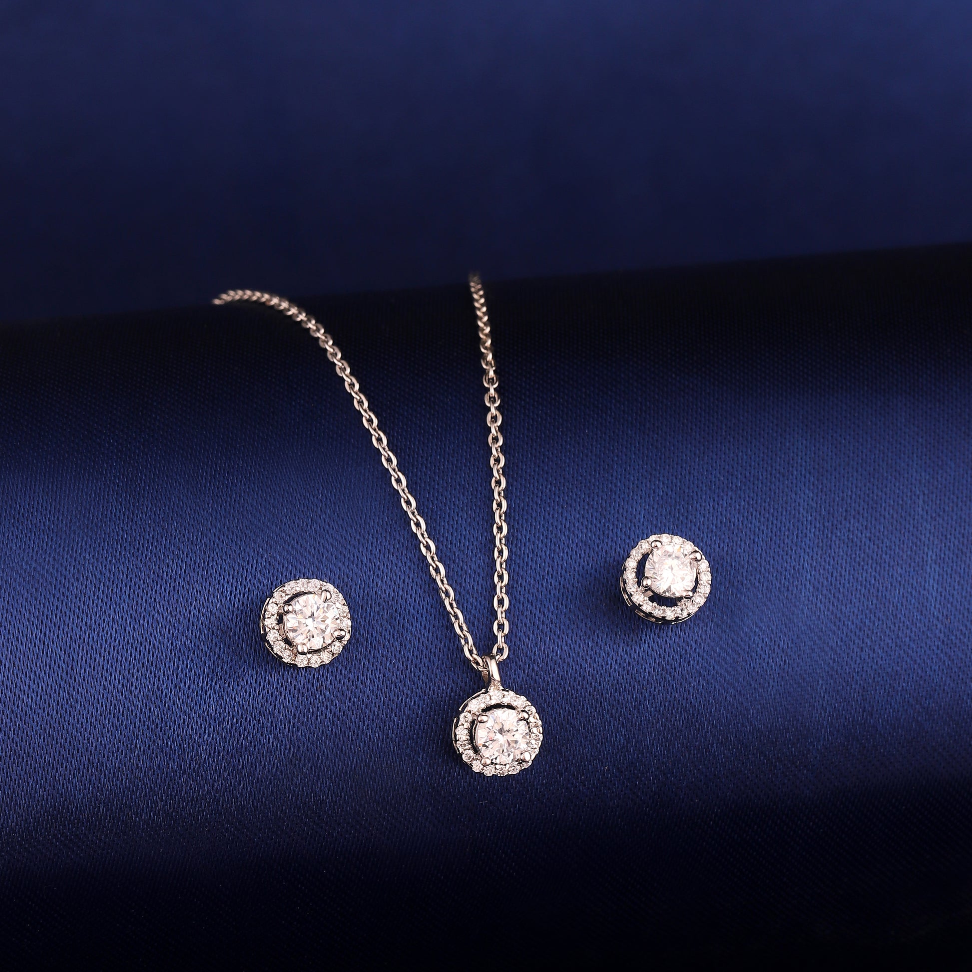 Round halo 925 silver pendant and earrings styled on dark background